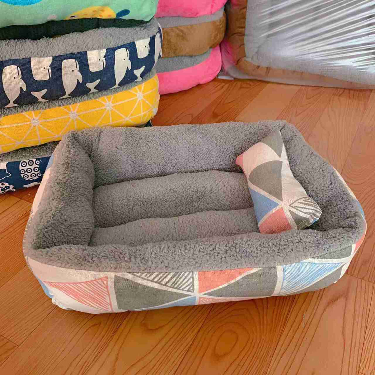 Gray fleece pet bed with colorful fish pattern and small pillow