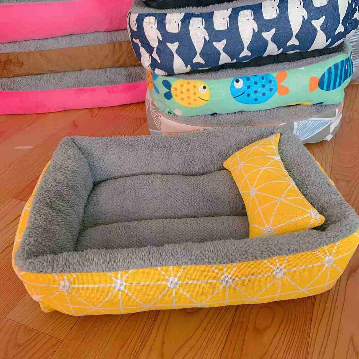 Gray plush pet bed with fish-themed pillow and colorful fabric sides