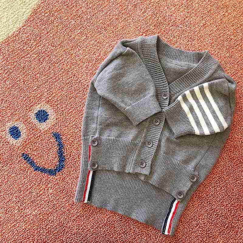 Gray cardigan sweater for pets with buttons and striped accents on a textured background