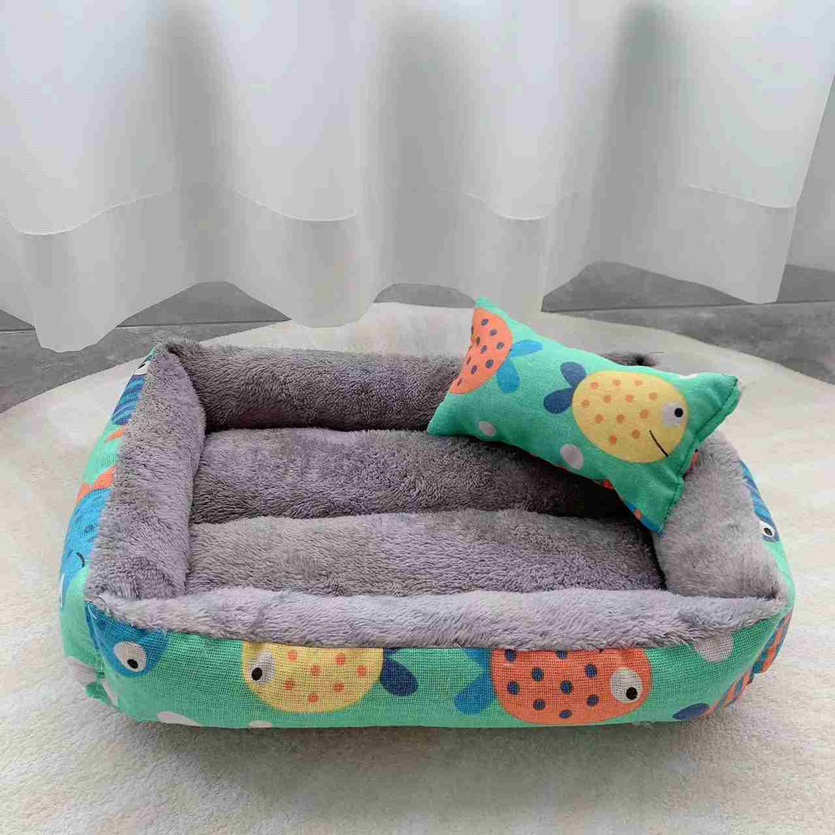 Gray fleece pet bed with colorful fish pattern and small pillow